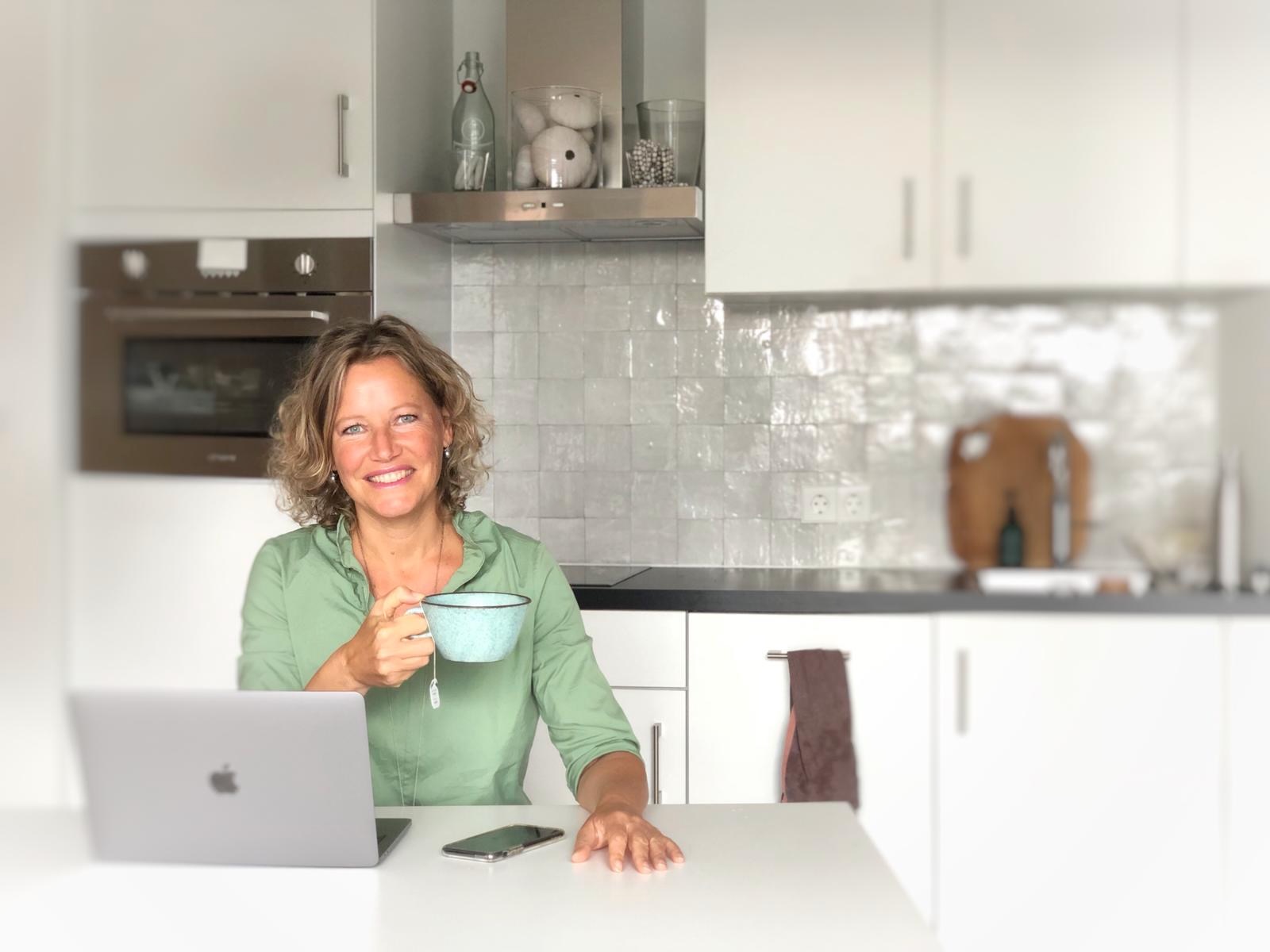 Esther Jacobs aan de keukentafel met laptop en thee