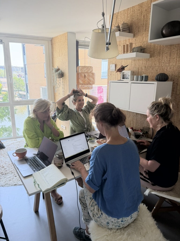 Deelnemers werken tijdens de AI-dag met laptops aan tafel