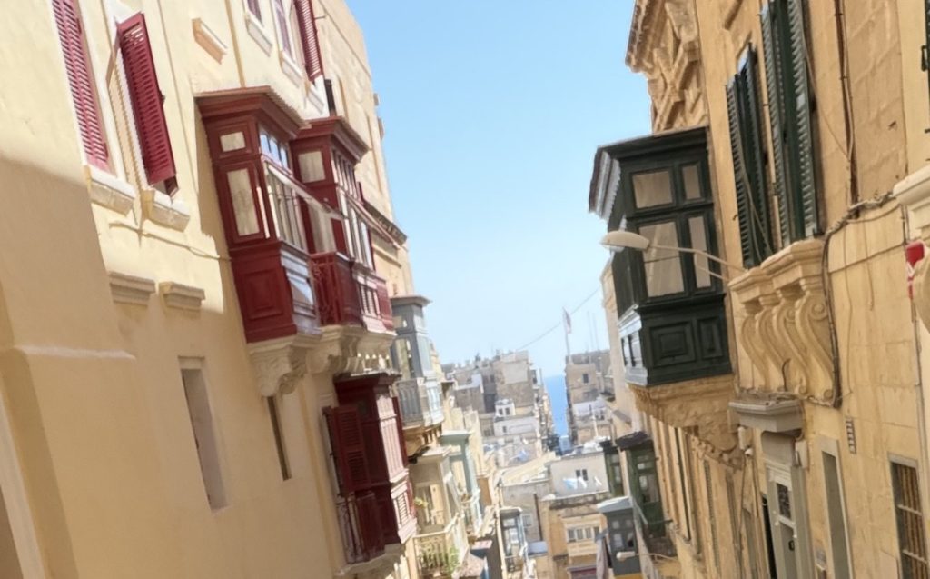 Traditional enclosed wooden balconies on a street in Malta