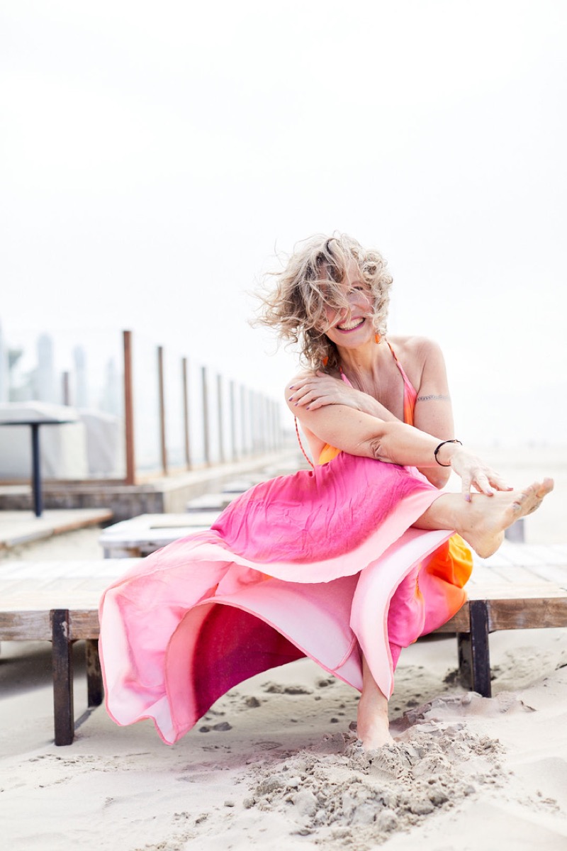 Esther Jacobs lachend in een roze jurk op het strand
