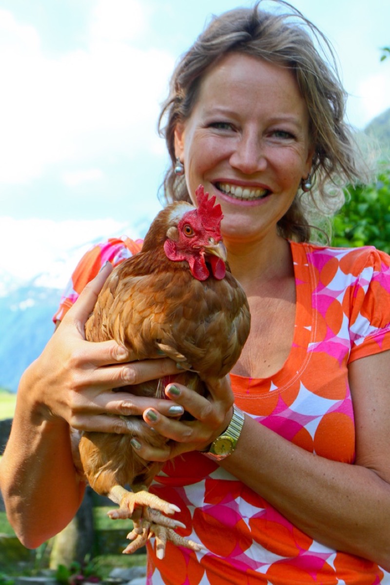 Esther Jacobs lachend met een kip in haar armen