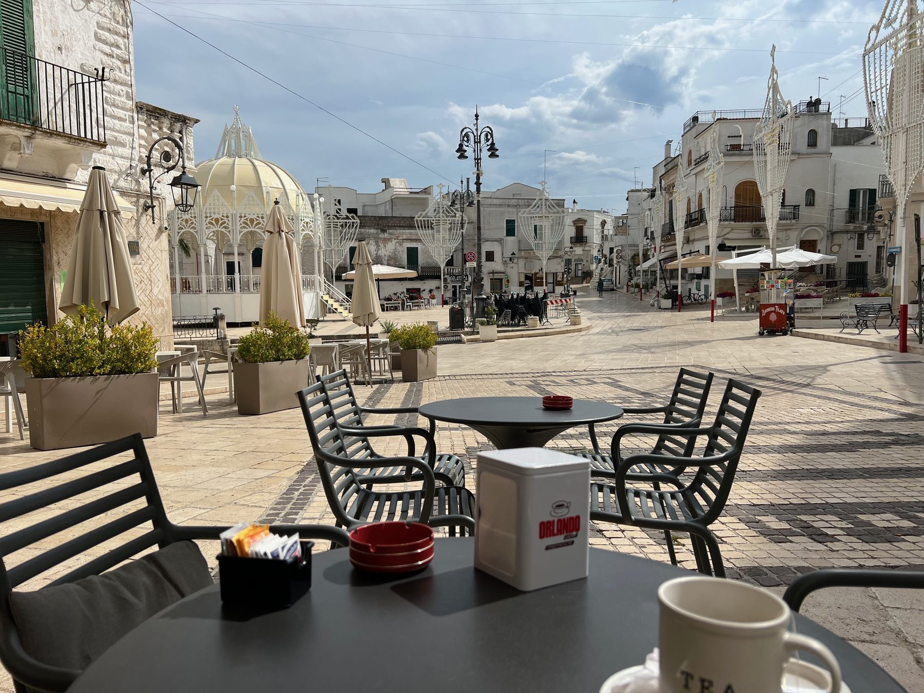 Een zonnig plein met witte huizen en terrassen in Ceglie Messapica.