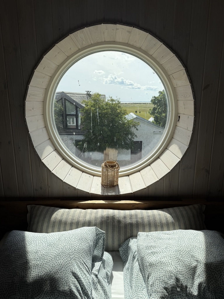 The Surrender Experiment – room A cosy room with a round window overlooking the island